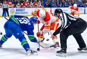 Elias Lindholm #23 of the Vancouver Canucks and Nazem Kadri #91 of the Calgary Flames face off during the second period of their NHL game at Rogers Arena on March 23, 2024 in Vancouver, British Columbia, Canada.