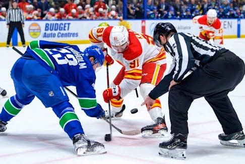 Elias Lindholm #23 of the Vancouver Canucks and Nazem Kadri #91 of the Calgary Flames face off during the second period of their NHL game at Rogers Arena on March 23, 2024 in Vancouver, British Columbia, Canada.