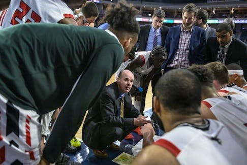 Dave Smart, middle, speaks to Carleton Ravens playerse during a timeout of quarterfinal action against the Alberta Golden Bears in the USports men's basketball national championship in Halifax on March 8, 2019.