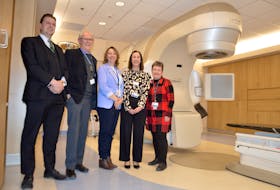 From left, Cape Breton Cancer Centre team members Tom Ashford (radiation oncology manager), Dr. Elwood MacMullin (medical director), Rhonda McNeil (health service manager of medical oncology and hematology), Robyn LeBlanc (assistant health services manager) and Valerie Nugent (Nova Scotia Health Authority eastern zone director of cancer care and palliative care) stand in front of the linear accelerator at the cancer centre. Stereotactic body radiation therapy can reduce treatment from several weeks to a few days, resulting in fewer side effects and a better quality of life for patients. Chris Connors/Cape Breton Post