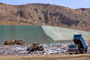 Workers use heavy machinery to move trash and waste at the Frank R. Bowerman landfill on Irvine, California, U.S., June 15, 2021.Picture taken June 15, 2021. 