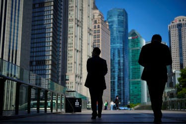 People walk by office towers in the Lujiazui financial district of Shanghai, China October 17, 2022.