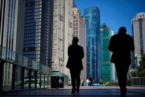 People walk by office towers in the Lujiazui financial district of Shanghai, China October 17, 2022.