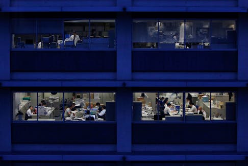 Office workers are pictured through building windows during dusk in Tokyo March 3, 2015.  