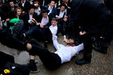 A protester is taken away as Ultra-Orthodox Jewish men protest against attempts to change government policy that grants ultra-Orthodox Jews exemptions from military conscription, in Jerusalem, March 18, 2024.