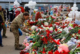 A man lays flowers at a makeshift memorial near the Crocus City Hall following a deadly attack on the concert venue outside Moscow, Russia, March 26, 2024.