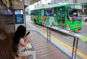 A woman waits for the bus inside a glass-covered stop in which a thermal imaging camera, UV sterilizer, air conditioner, CCTV and digital signage are set, to avoid the spread of COVID-19 in Seoul, South Korea, August 14, 2020.