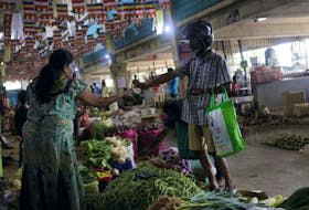 A customer pays for the vegetables he bought at a stall at a main market in Colombo, Sri Lanka June 1, 2023.