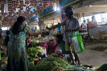 A customer pays for the vegetables he bought at a stall at a main market in Colombo, Sri Lanka June 1, 2023.