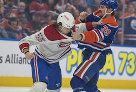 Sam Carrick (39) of the Edmonton Oilers, grapples with Michael Pezzetta (55) of the Montréal Canadiens at Rogers Place in Edmonton on March 19, 2024.
