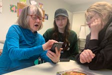 Ann Louise MacNeil, 73, from left, organizes the photos on her smartphone into albums as Breton Education Centre students Amy Darling and Addison MacDonald look on during Tech Tea with Teens at the New Waterford library on Wednesday. “I've got over 1,000 pictures and I never know where any of them are. Now I know I can find them,” said MacNeil. CHRIS CONNORS/CAPE BRETON POS