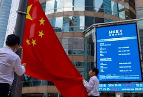 Staff lower Chinese national flag in front of screens showing the index and stock prices outside Exchange Square, in Hong Kong, China, August 18, 2023.