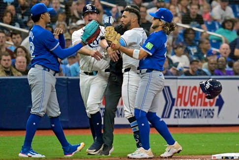 Tampa Bay Rays third base coach Brady Williams, center left, and shortstop Bo Bichette, right, try to break up a confrontation between Tampa Bay's Jose Caballero, center right, and Toronto Blue Jays reliever Genesis Cabrera, left, after Cabrera pushed Caballero during the seventh inning of a baseball game, Saturday, March 30, 2024, in St. Petersburg, Fla.  