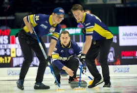 Nova Scotia skip Matthew Manuel, centre, watches his shot as lead Nick Zachernuk and second Jeffrey Meagher sweep during action against Alberta on Monday at the Montana's Brier in Regina. - Michael Burns / Curling Canada