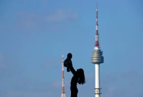 A woman holding up her baby is silhouetted against the backdrop of N Seoul Tower, commonly known as Namsan Tower, in Seoul, South Korea. South Korea's fertility rate, already the world's lowest, continued its dramatic decline in 2023. REUTERS/Kim Hong-Ji
