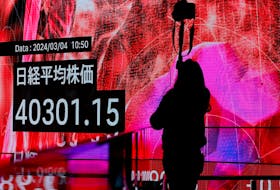 A photographer takes a photo of an electronic screen displaying Japan's Nikkei share average in Tokyo, Japan, March 4, 2024.