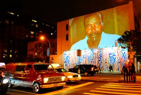 Passersby walk under a projection that is part of the non-profit organization Invisible Children's "Kony 2012" viral video campaign, in New York April 20, 2012.