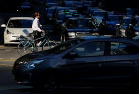 A commuter pushes his bicycle past cars stopping at a traffic light during morning rush hour in Singapore June 16, 2017.