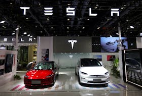 A staff member looks at Tesla's new Model 3 sedan displayed next to Model X SUV at the China International Fair for Trade in Services (CIFTIS) in Beijing, China September 2, 2023.