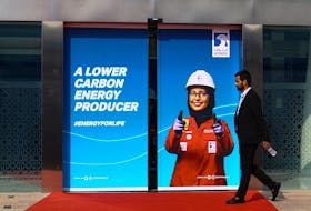 A person walks past a Abu Dhabi National Oil Company (ADNOC) poster during the Abu Dhabi International Petroleum Exhibition and Conference (ADIPEC) in Abu Dhabi, United Arab Emirates, October 31, 2022.