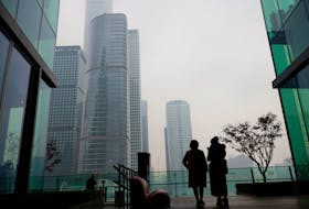 People look at the skyline of the central business district (CBD), on the day of the opening session of the National People's Congress (NPC), during a hazy day in Beijing, China, March 5, 2021.