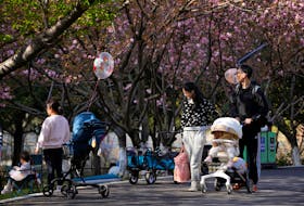 A parents pushes a stroller with a baby in a park in Shanghai, China, April 2, 2023.