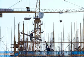 A Vanke sign is seen above workers working at the construction site of a residential building in Dalian, Liaoning province, China September 16, 2019.