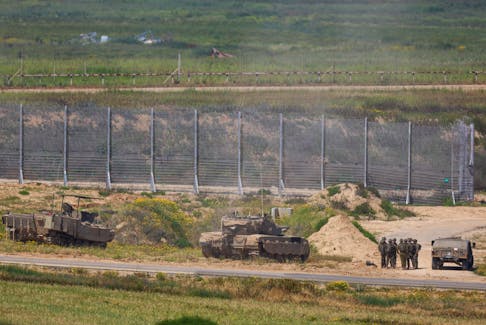 Israeli soldiers stand near military vehicles amid the ongoing conflict between Israel and the Palestinian Islamist group Hamas, near the Israel-Gaza border, as seen from Israel, April 4, 2024. REUTERS/Hannah McKay