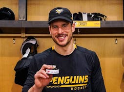 Pittsburgh Penguins centre Sidney Crosby holds the puck from his 1,000th career assist. - Pittsburgh Penguins