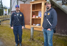 Volunteer firefighters with the Albert Bridge department Dan MacMillan, left, and Tyler Naugler stand next to the nearly empty food cupboard outside their station. Misuse of the outdoor cupboard, meant to help people dealing with food insecurity, has led to the department's decision to close it. NICOLE SULLIVAN/CAPE BRETON