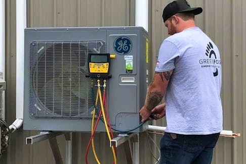 Jerad Wilson, a technician with Greenfoot Energy Solutions in Fredericton, works on a heat pump.