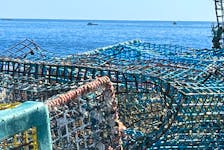 Lobster fishing boats check their gear near the Baccaro Point coastline, where stacks of derelict lobster traps, retrieved during a recent shoreline clean-up, wait to be collected.  Kathy Johnson