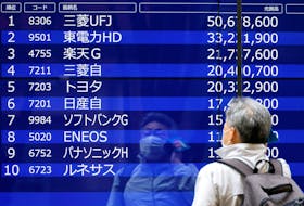 A man is reflected on an electric monitor displaying a stock quotation board outside a bank in Tokyo, Japan, June 5, 2023.