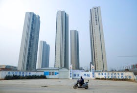 A man rides a scooter past apartment highrises that are under construction near the new stadium in Zhengzhou, Henan province, China, January 19, 2019.  Picture taken January 19, 2019. 