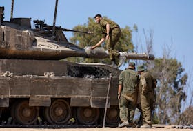 Israeli soldiers stand next to a tank, near the Israel-Gaza border, amid the ongoing conflict between Israel and the Palestinian Islamist group Hamas, in Israel, April 15, 2024.