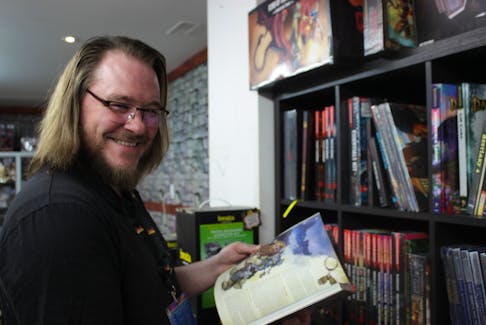 Brandon Massey holds a guidebook for Dungeons and Dragons. Guide books have hundreds of differing rules that change depending on the edition, time of publishing and group that publishes them. Justine Talla • Special to The Guardian