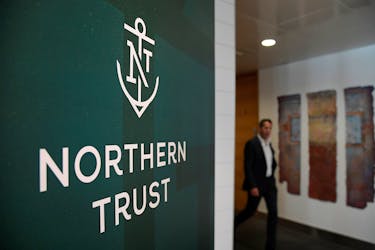 An employee walks past a company logo at Northern Trust offices in London, Britain August 1, 2019. Picture taken August 1, 2019.