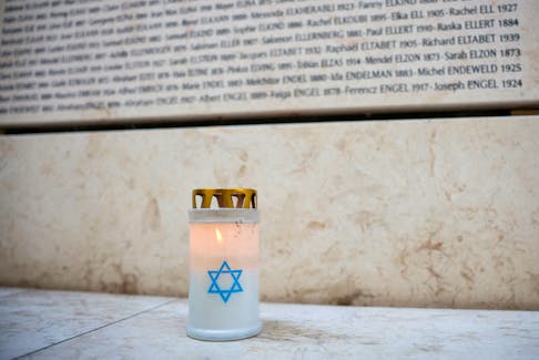 A candle is seen in front of the Wall of Names at the Shoah Memorial as France commemorates the 80th anniversary of the Vel d'Hiv roundup, in Paris, France, July 12, 2022.