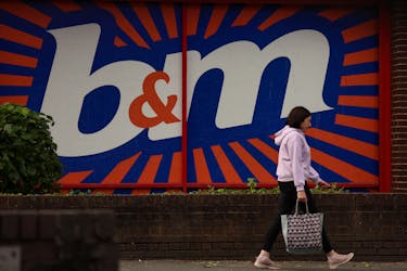A woman carrying a shopping bag walks past a B&M store in Manchester, Britain June 1, 2023.