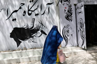 An Afghan woman walks past a beauty salon in Kabul, Afghanistan, July 6, 2023.