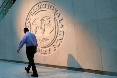 A man walks past the International Monetary Fund (IMF) logo at its headquarters in Washington, U.S., May 10, 2018.