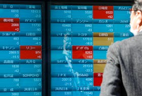 A man watches stock quotations on an electronic board outside a brokerage, in Tokyo, Japan, March 20, 2023.