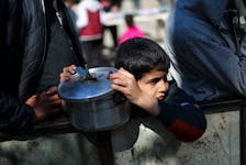 A Palestinian child waits to receive food cooked by a charity kitchen amid shortages of food supplies, as the ongoing conflict between Israel and the Palestinian Islamist group Hamas continues, in Rafah, in the southern Gaza Strip, February 5, 2024.