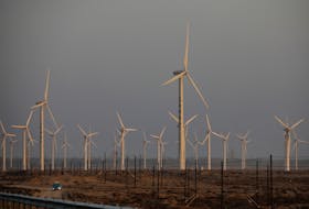 A car drives near wind turbines on a power station near Yumen, Gansu province, China September 29, 2020. Picture taken September 29, 2020.