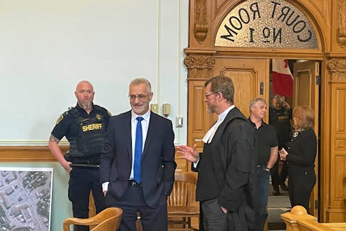 Lawyer Robert Regular (second from left), who is facing charges of sexual assault and sexual interference, speaks with his lawyer, Jerome Kennedy Thursday in court in St. John's. Evan Careen • The Telegram
