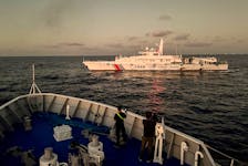 Members of the media take footage of a Chinese Coast Guard vessel blocking a Philippine Coast Guard vessel on its way to a resupply mission at Second Thomas Shoal in the South China Sea, March 5, 2024.