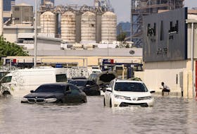A person sits near vehicles stranded in flood water caused by heavy rains in Dubai, United Arab Emirates, April 17, 2024.