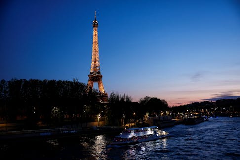 A tourist boat travels on the River Seine near the Alma bridge with the Eiffel Tower in the background at night in Paris, France, April 18, 2024.