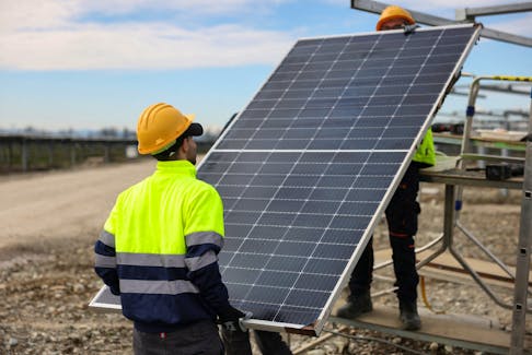 Two workers install a bifacial 540 W solar panel at a solar panels park by energy supplier Enel Green Power, in Trino Italy, March 5, 2024.