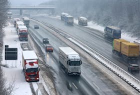 Vehicles pass trucks, parked at the emergency lane after heavy snowfall at the A3 highway, near Aegidinberg, Germany, January 18, 2024.    